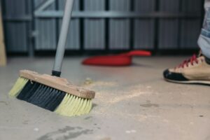 Cleaning sawdust from the floor with a broom. Cleaning up trash after work