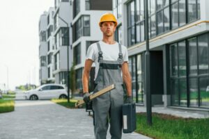 Finished buildings. Young man working in uniform at construction at daytime